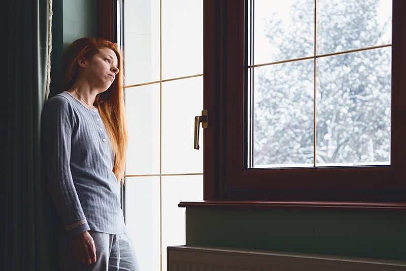Woman looks out the window in the winter