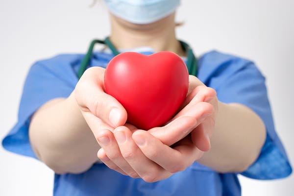 woman in medical scrubs holding a toy red heart