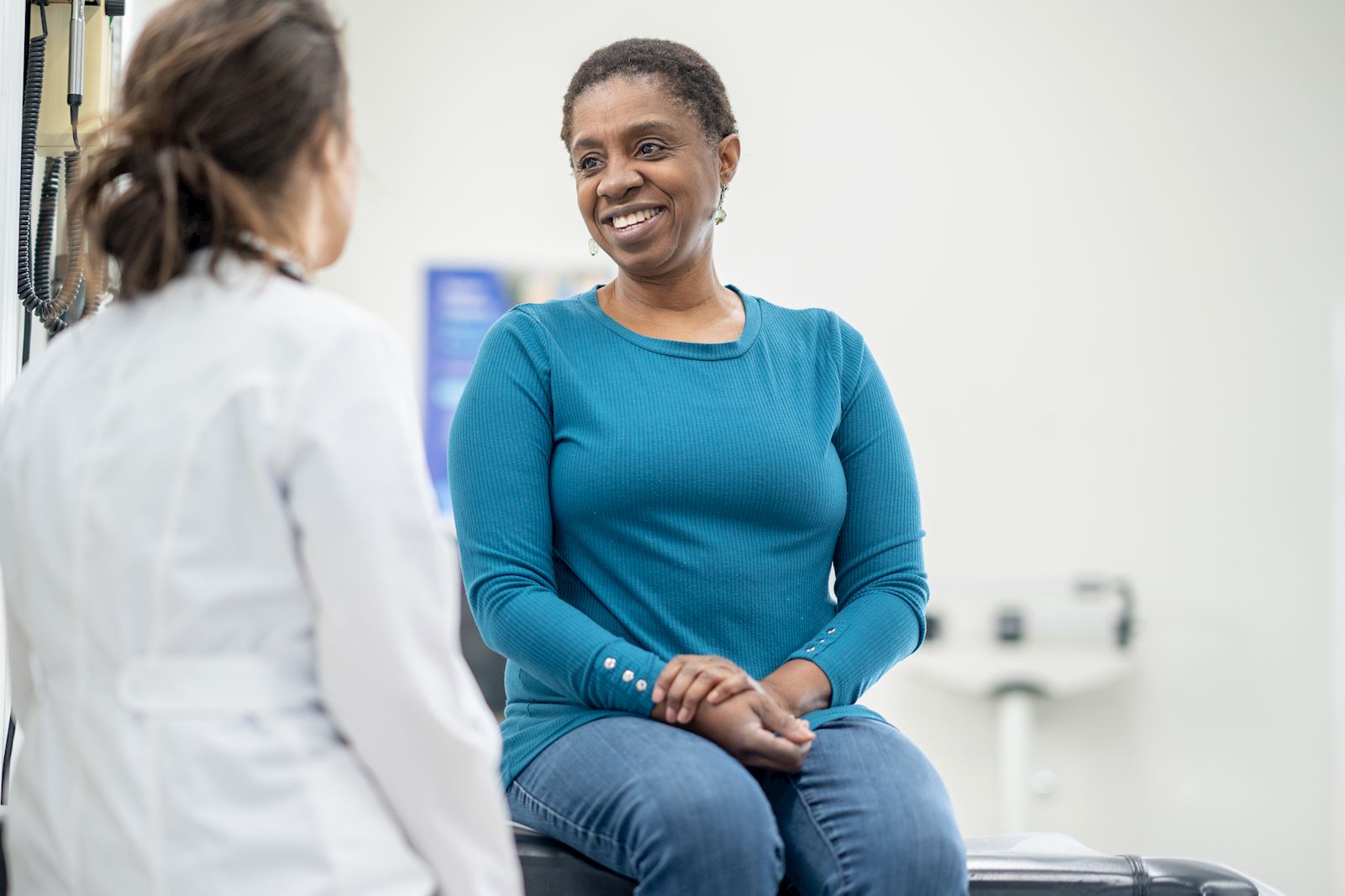 woman sitting in exam room talking with female doctor