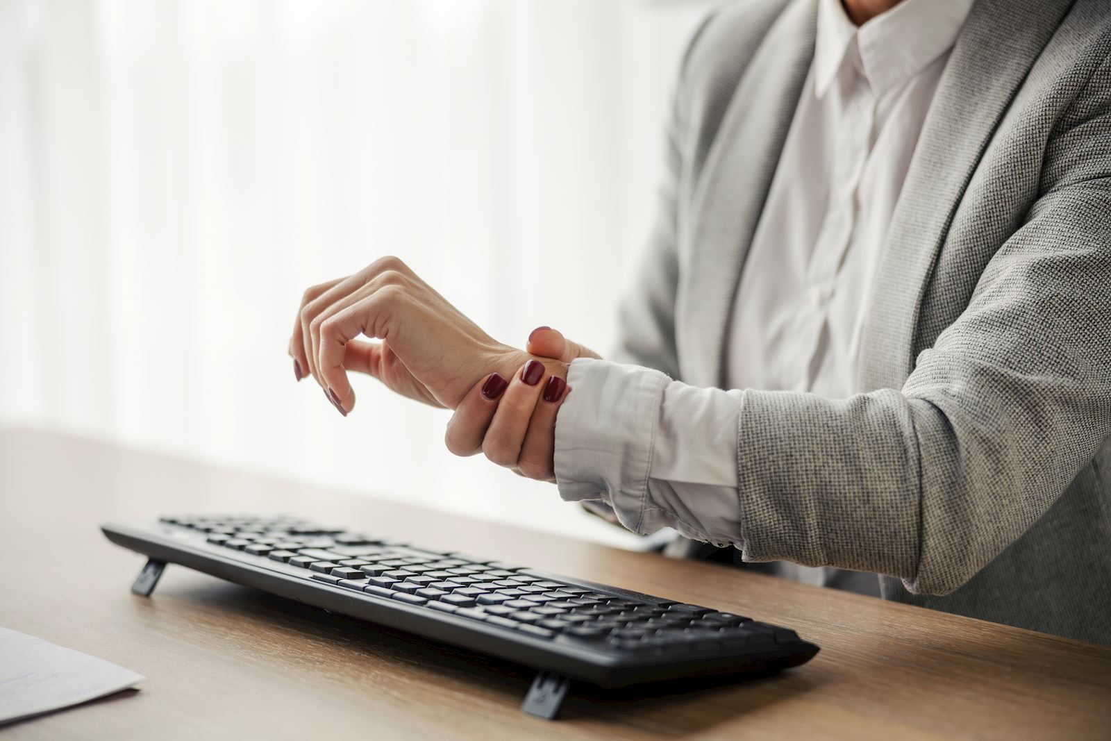 person holding their wrist at a desk