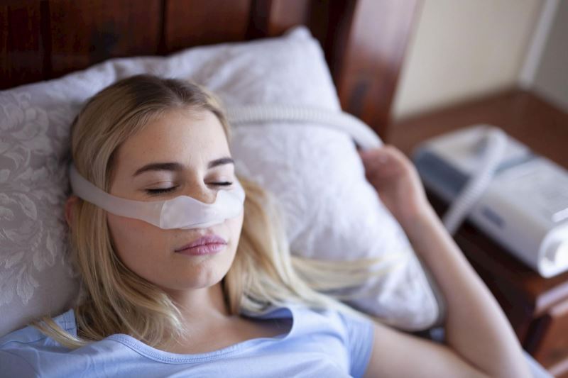 Woman sleeps while wearing a CPAP machine