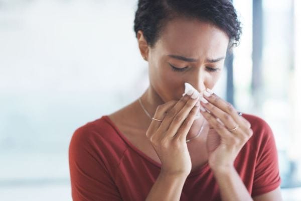 woman sneezes into tissue