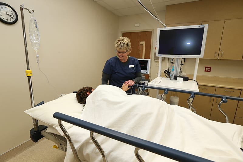 Nurse calmly holding patients hand before a colonoscopy