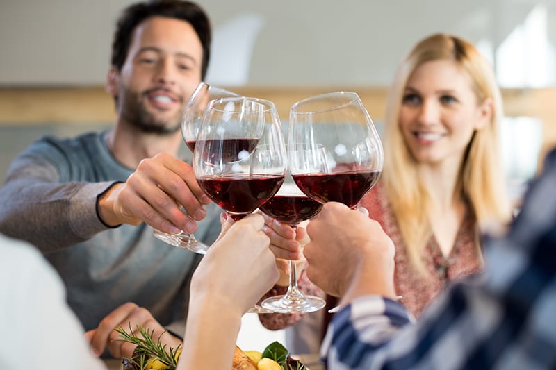 Friends clinking glasses of red wine together