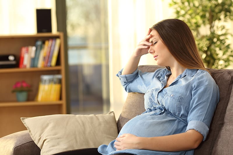 Pregnant woman sitting, looking stress and slightly in pain
