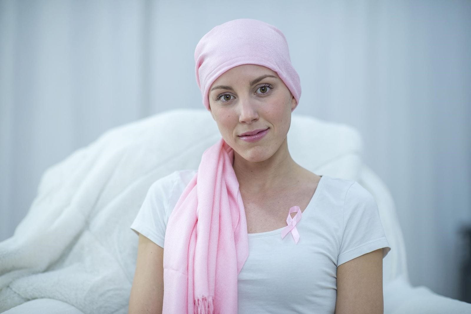 Breast cancer survivor wearing pink headscarf and pink ribbon