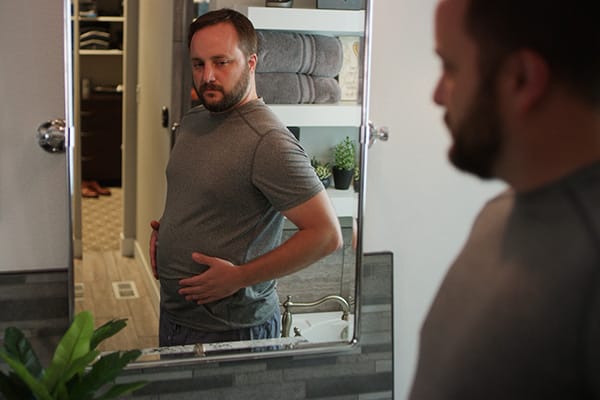 Man looking at his belly in a mirror