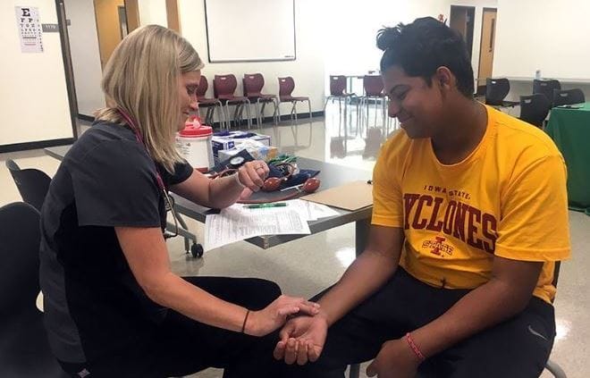 A nurse checks a students pulse at sports physicals