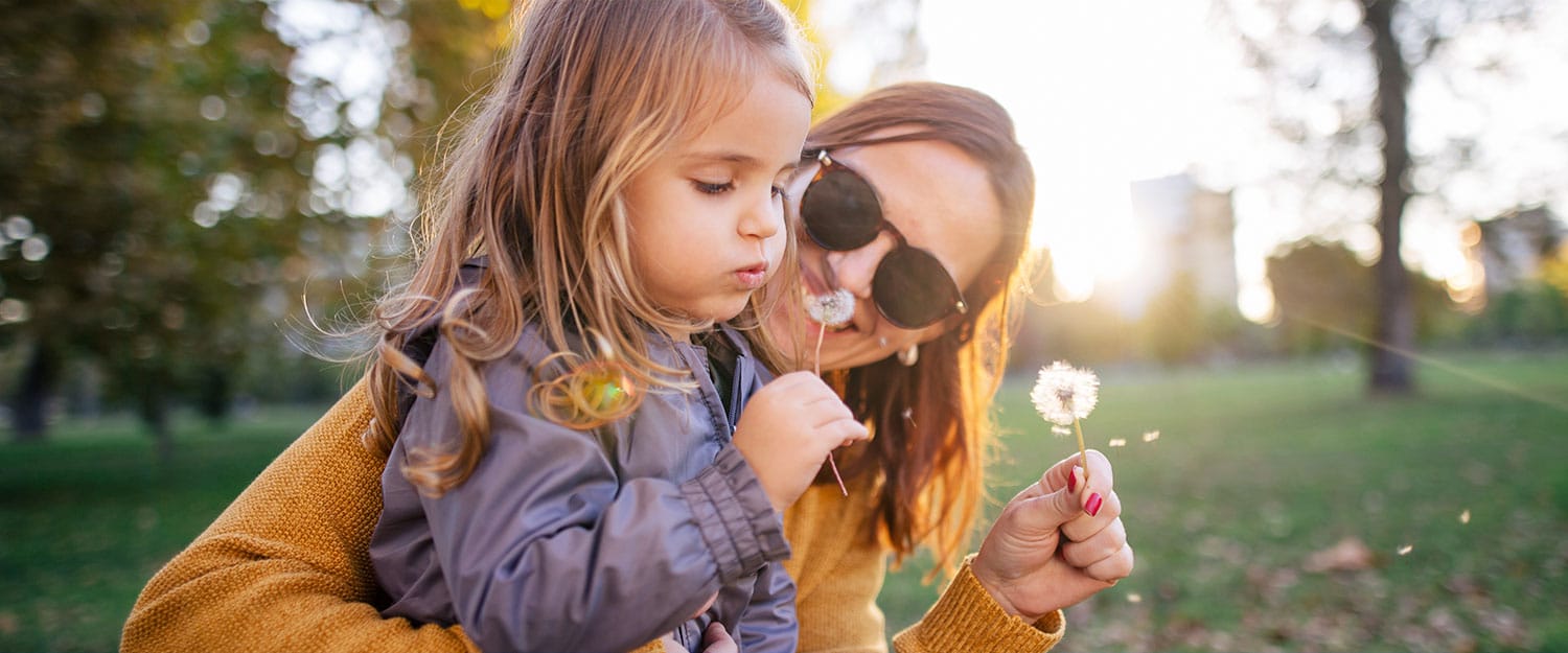 Mom and daughter blowing on dandelion