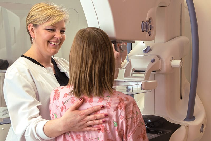 Provider smiling at woman receiving mammogram