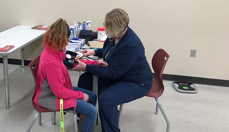 nurse checking blood pressure of teenage female