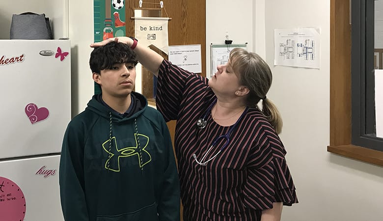 nurse measuring height of teen